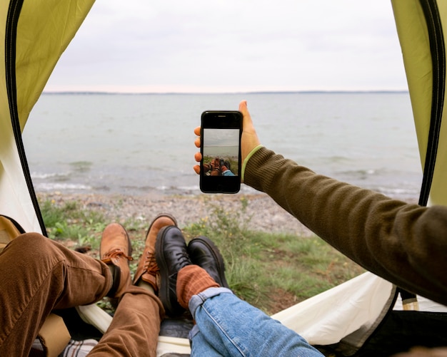 テントの中でスマートフォンで自分撮りを撮るカップル