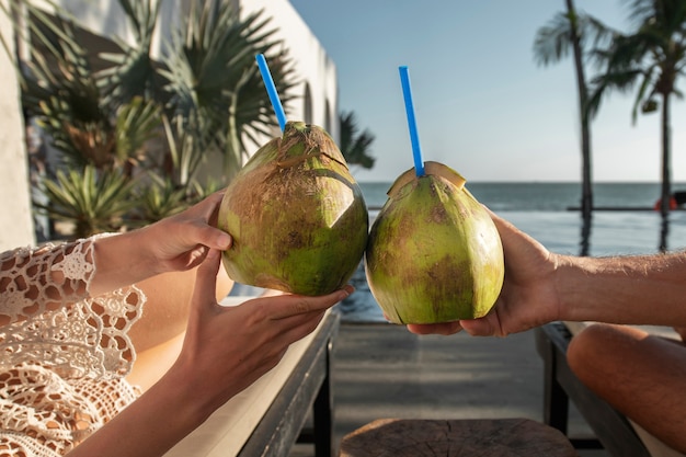 Couple talking and drinking coconut milk by the pool during vacation