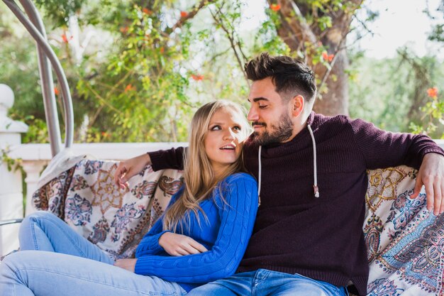 Couple talking on swing sofa on veranda