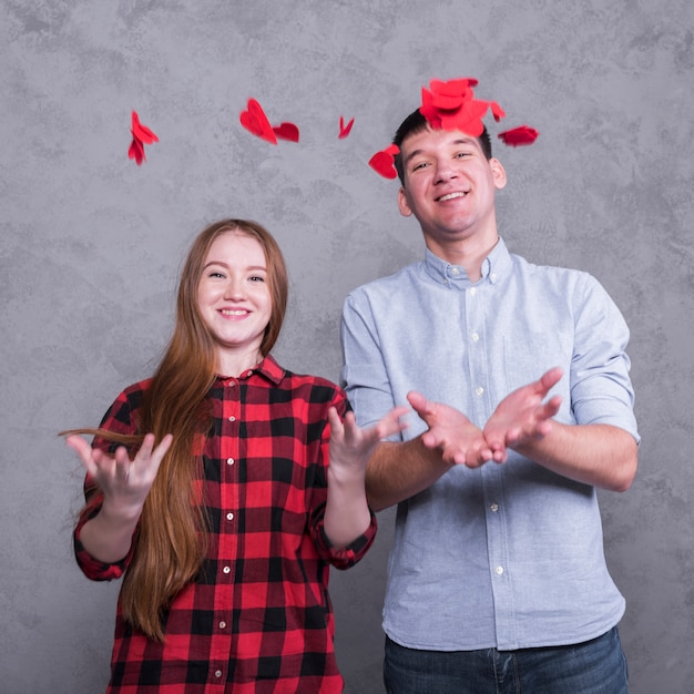 Couple throwing up red paper hearts 