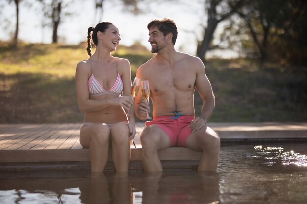 Couple toasting glasses of champagne in pool