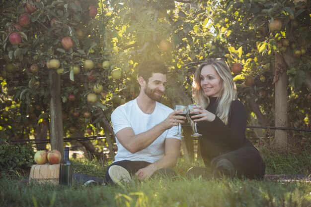 Couple toasting glasses of wine in apple orchard