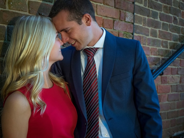 Free photo couple touching foreheads standing near a stone wall