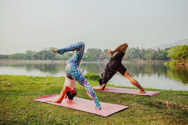 Couple training yoga next to the lake