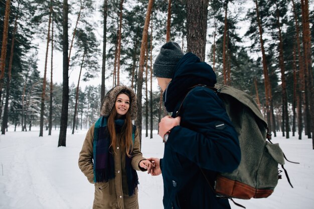 Couple of travelers in winter clothes walking in snowy forest