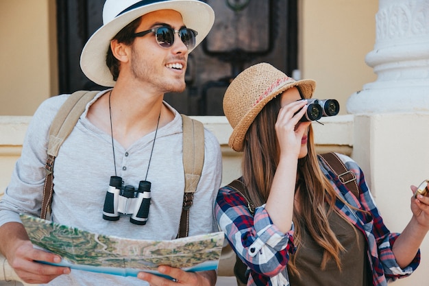 Foto gratuita coppia di viaggiatori con binocolo, mappa e occhiali da sole