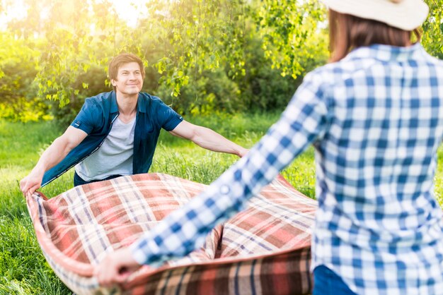 Couple unfolding picnic blanket