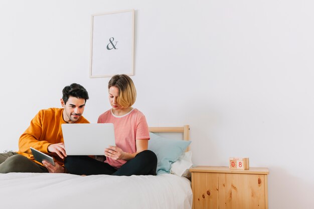 Couple using laptop in bedroom