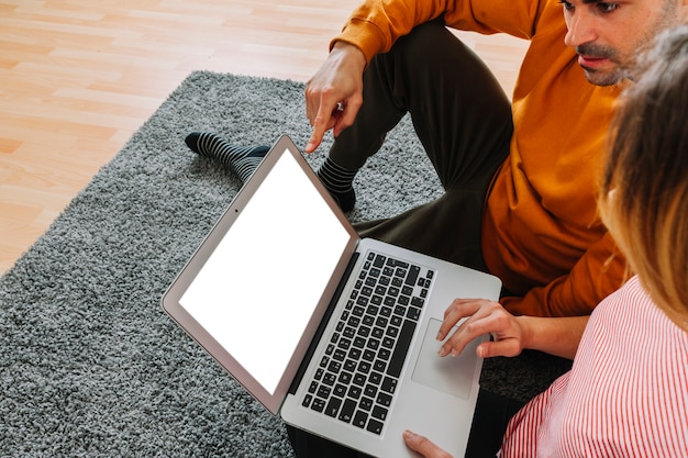 Couple using laptop on carpet