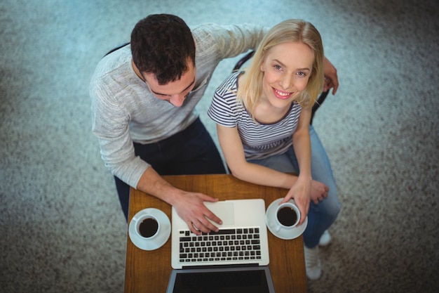 Couple using laptop while having black coffee in cafÃ©