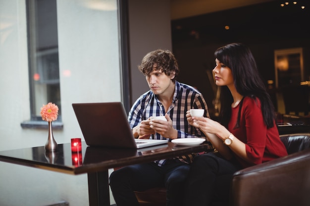 Couple using laptop while having coffee