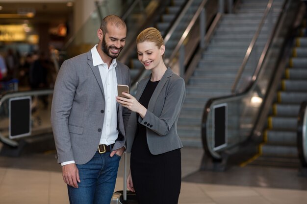 空港で携帯電話を使用しているカップル