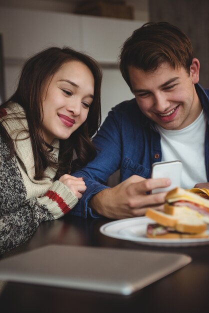 Couple using mobile phone while having breakfast