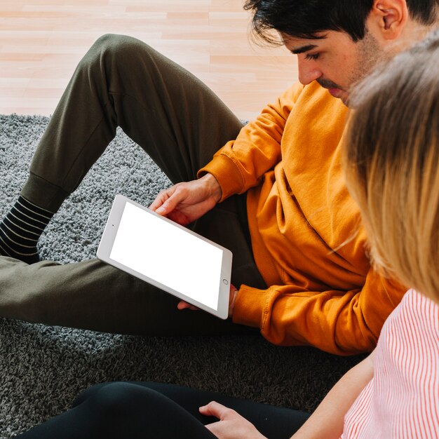 Couple using tablet on carpet