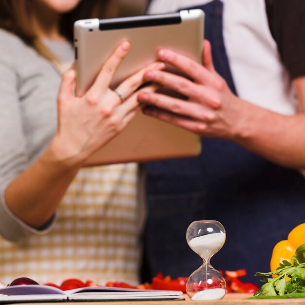 Couple using tablet while hourglass is on