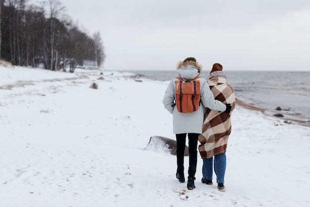 Couple waking by the beach together while on a winter road trip