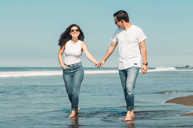 Couple walking along seaside barefoot in water