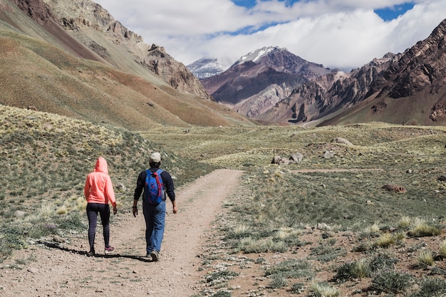Couple walking on dirt track near mountain range