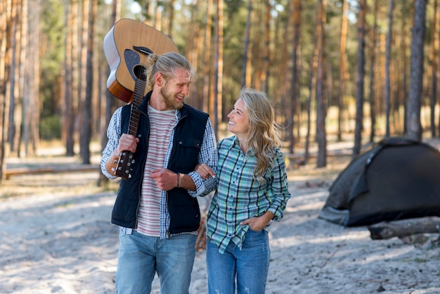 Foto gratuita coppie che camminano nella foresta con la chitarra