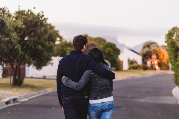 Couple walking holding on couple walking holding on waist by a roadwaist by a road