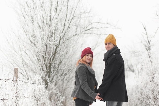 Free photo couple walking outdoor in winter and looking behind medium shot