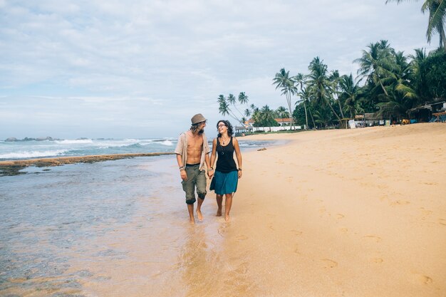 砂の海岸を歩いているカップル