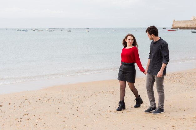 Пара гуляет и разговаривает на песчаном берегу моря