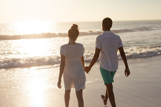 Couple walking together hand in hand on the beach