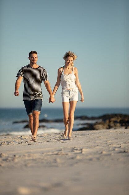 Couple walking together hand in hand on the beach