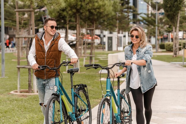 外で自転車を持って歩いているカップル