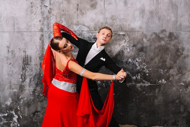 Couple waltzing near gray wall