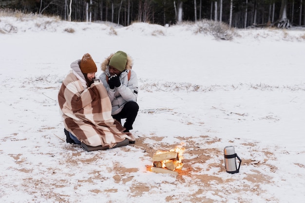 겨울 도로 여행을 하는 동안 해변에서 불 옆에서 워밍업하는 커플
