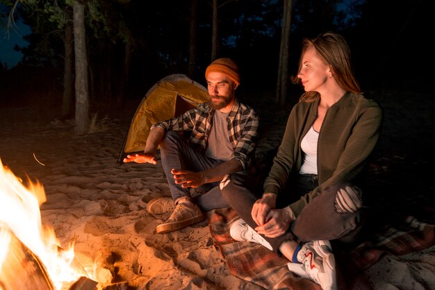 Couple warming up at night by a campfire