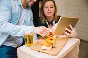 Free photo couple watching photos on tablet in cafe