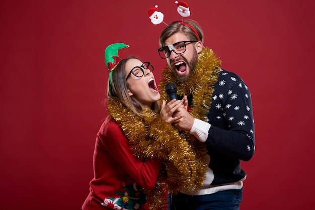 Couple wearing Christmas clothes has great fun while having karaoke performance