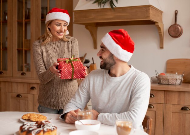 屋内でクリスマスの帽子をかぶっているカップル
