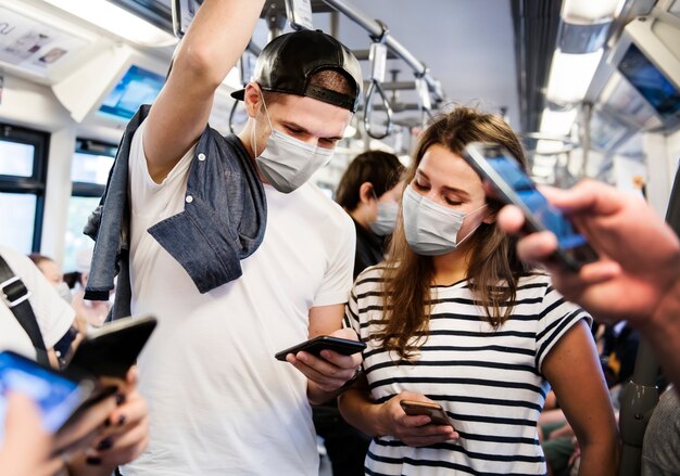 新しい通常の公共交通機関で旅行中に電車の中でマスクを着用しているカップル
