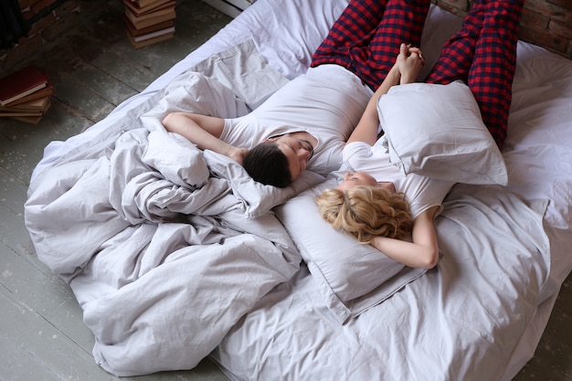 パジャマを着て、ベッドで寝ているカップル