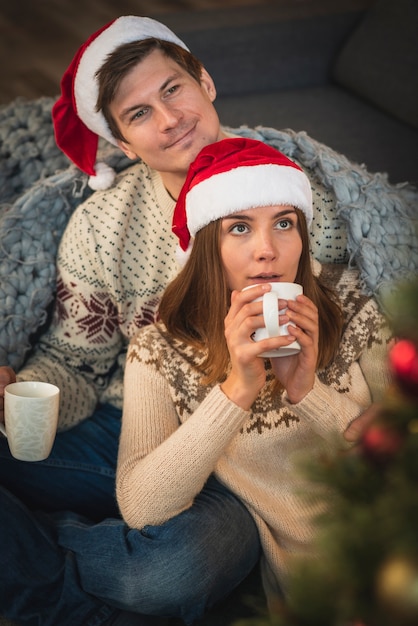 Couple wearing santa hats with hot drinks