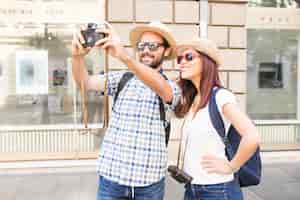 Free photo couple wearing sunglasses and hat taking selfie on camera