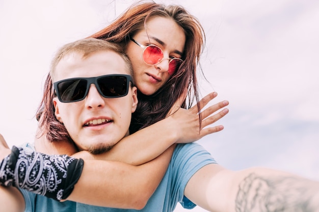 Foto gratuita coppia indossando occhiali da sole prendendo selfie contro il cielo