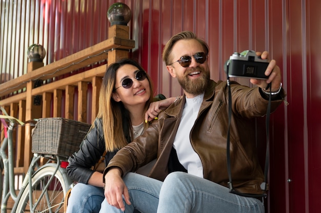 Couple wearing synthetic leather jackets taking selfie together outdoors