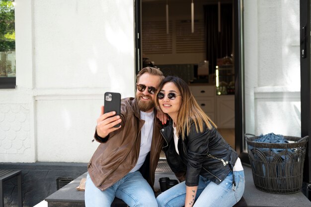 couple wearing synthetic leather jackets taking selfie together outdoors