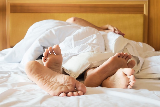 Couple on white bed in hotel room focus at feet