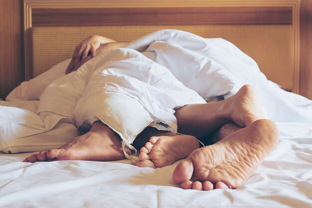 Пара на белой кровати в гостиничном номере сосредоточиться на ногах