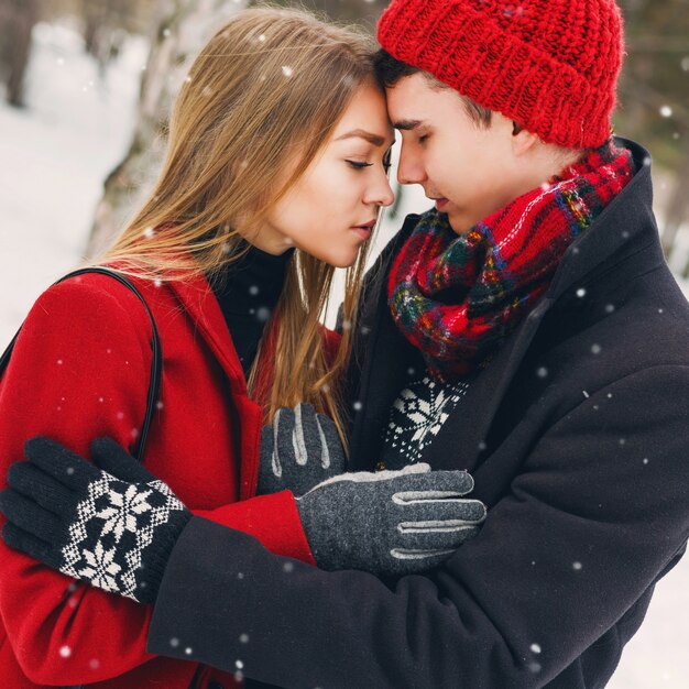 Couple in winter clothes hugging on a snowy day