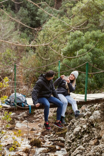 Couple with backpack sitting on bridge