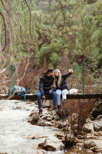 Couple with backpack sitting on bridge