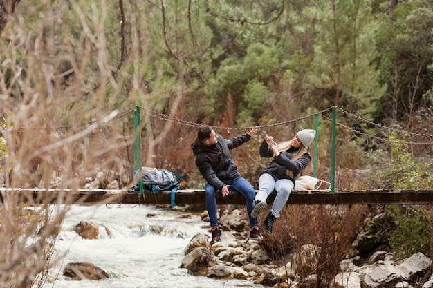 Couple with backpack sitting on bridge