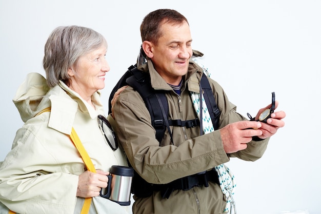 Free photo couple with backpacks looking at compass